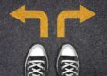 Pés apontados para dois caminhos com setas amarelas indicando direções opostas.