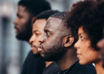 Grupo de pessoas negras olhando na mesma direção em um ambiente externo.